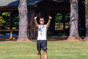 Camp Connect USA - A boy in a white shirt and shorts holding his thumbs up.