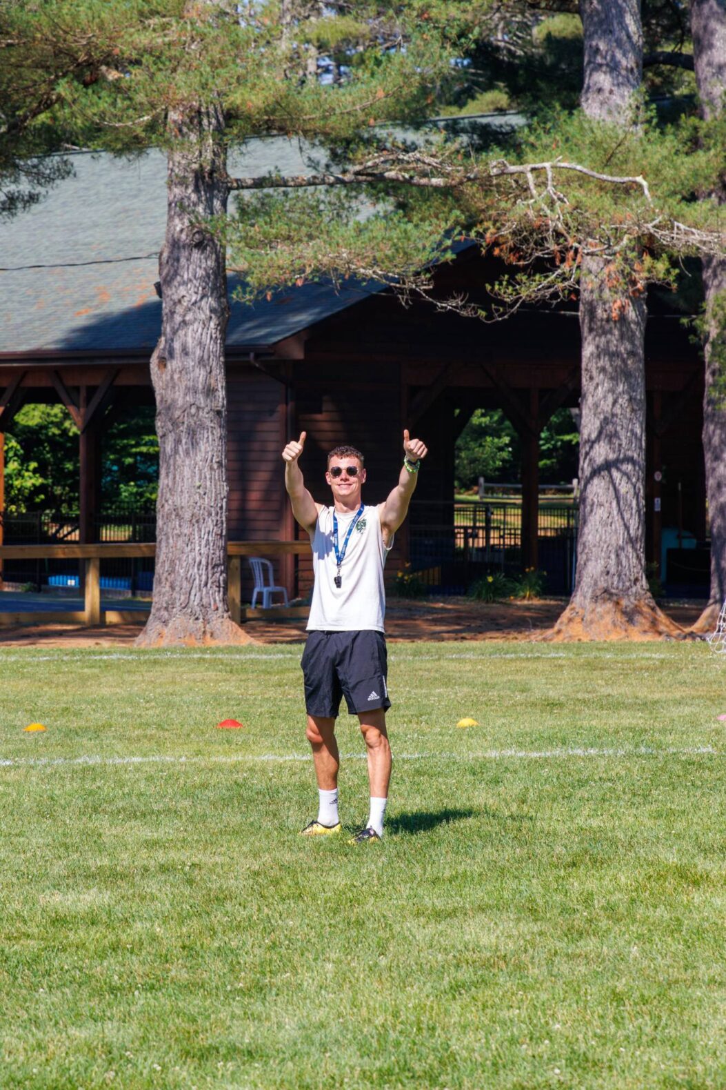 Camp Connect USA - A boy in a white shirt and shorts holding his thumbs up.