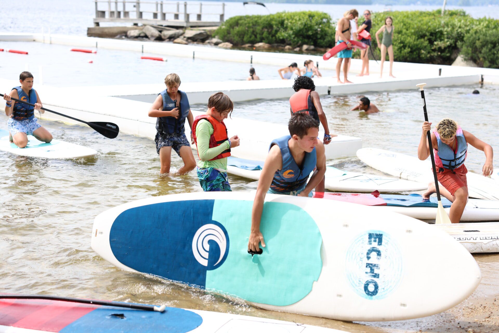 Camp Connect USA - Children and adults on a beach with paddleboards.