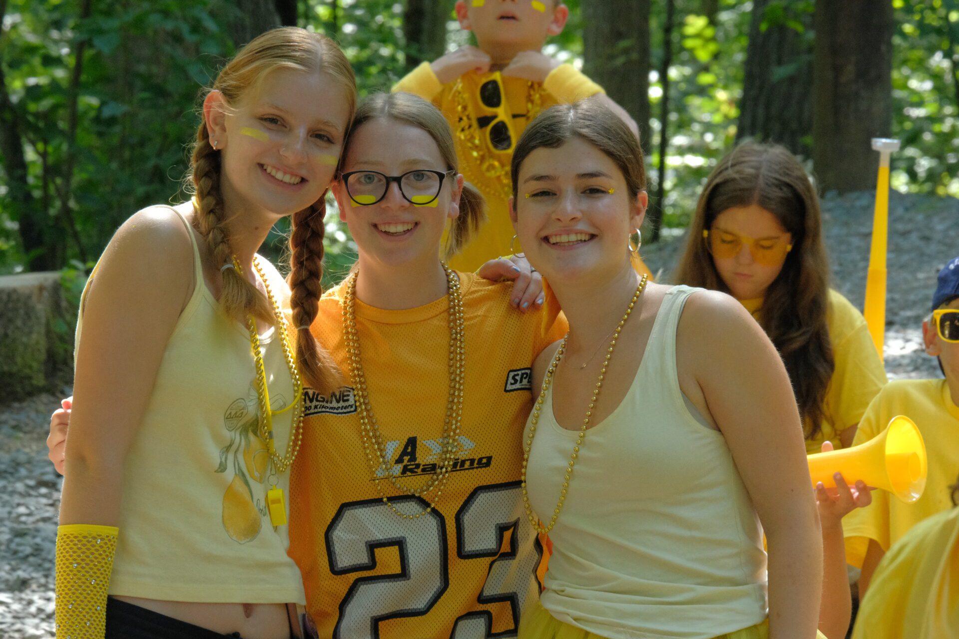 Camp Connect USA - Three smiling people in matching yellow shirts posing for a photo.