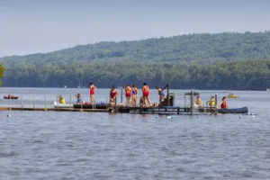 Camp Connect USA - Group of people in kayaks on a lake with mountains in the background.