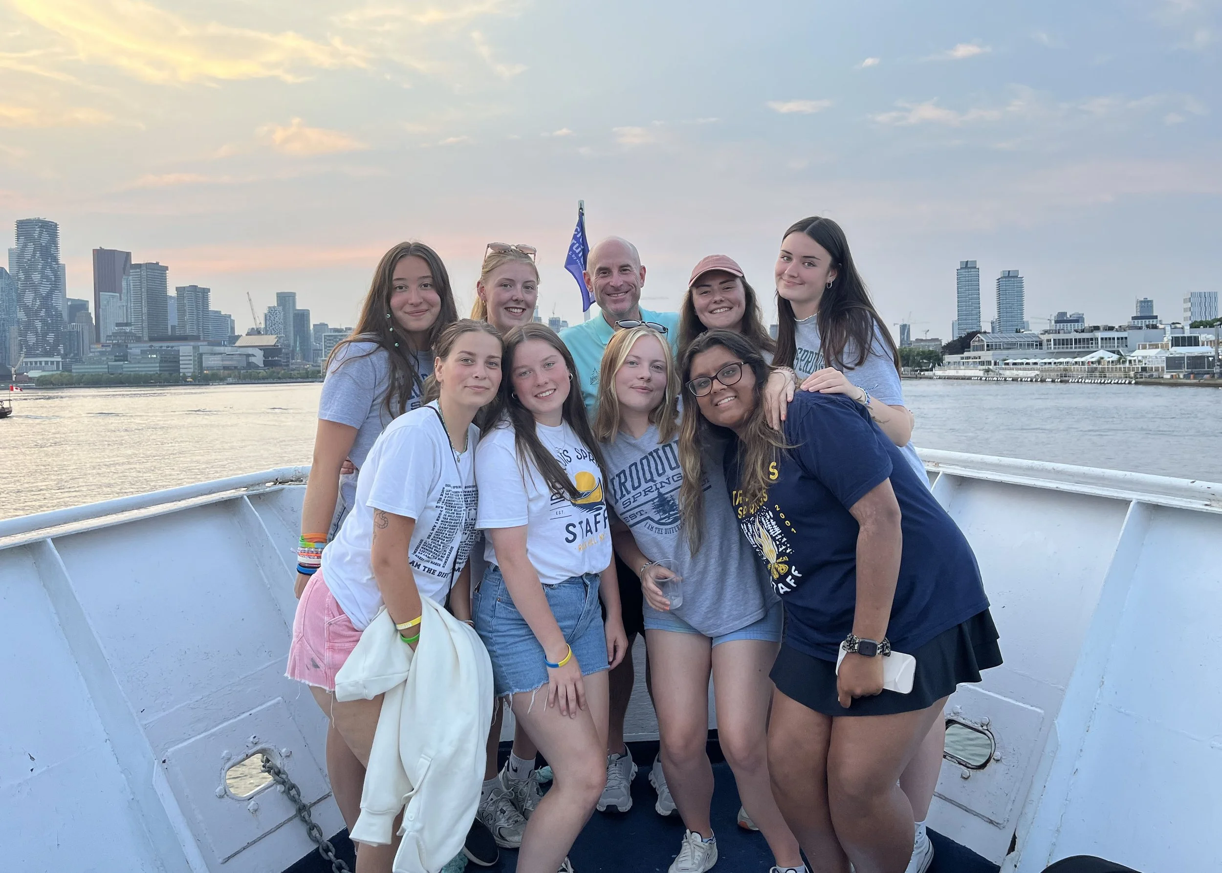 Camp Connect USA - Four people smiling on a boat with a city skyline in the background.